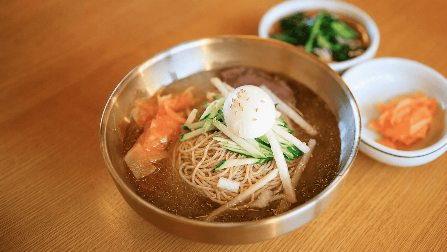 KYUNU Chuka Soba in dongchimi (water kimchi) broth with boiled egg, cucumbers, and Asian pear as toppings with a couple banchan sides.