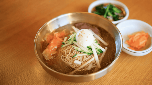 KYUNU Chuka Soba in dongchimi (water kimchi) broth with boiled egg, cucumbers, and Asian pear as toppings with a couple banchan sides.
