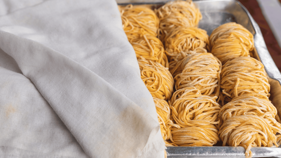 Bundles of fresh chuka soba noodles in a pan covered with a cloth