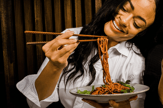 Woman eating Kyunu Rulebreaker Protein Noods, Beet Flavor with Skinny Chili Crisp