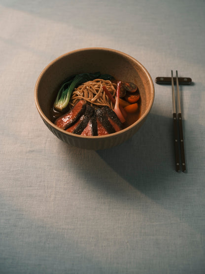 Taiwanese tomato beef noodle soup with sliced beef, bok choy and tomato in a stoneware bowl