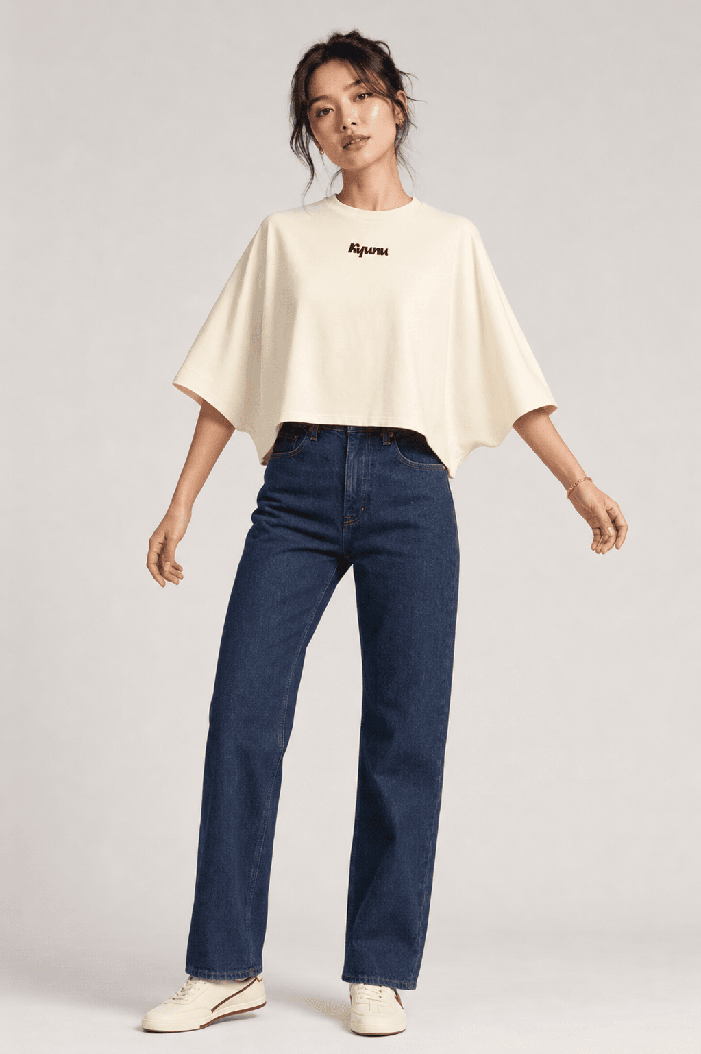 Model wearing the cream Kyunu batwing cropped tee with dark straight-leg jeans, front view