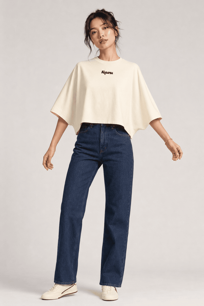 Model wearing the cream Kyunu batwing cropped tee with dark straight-leg jeans, front view
