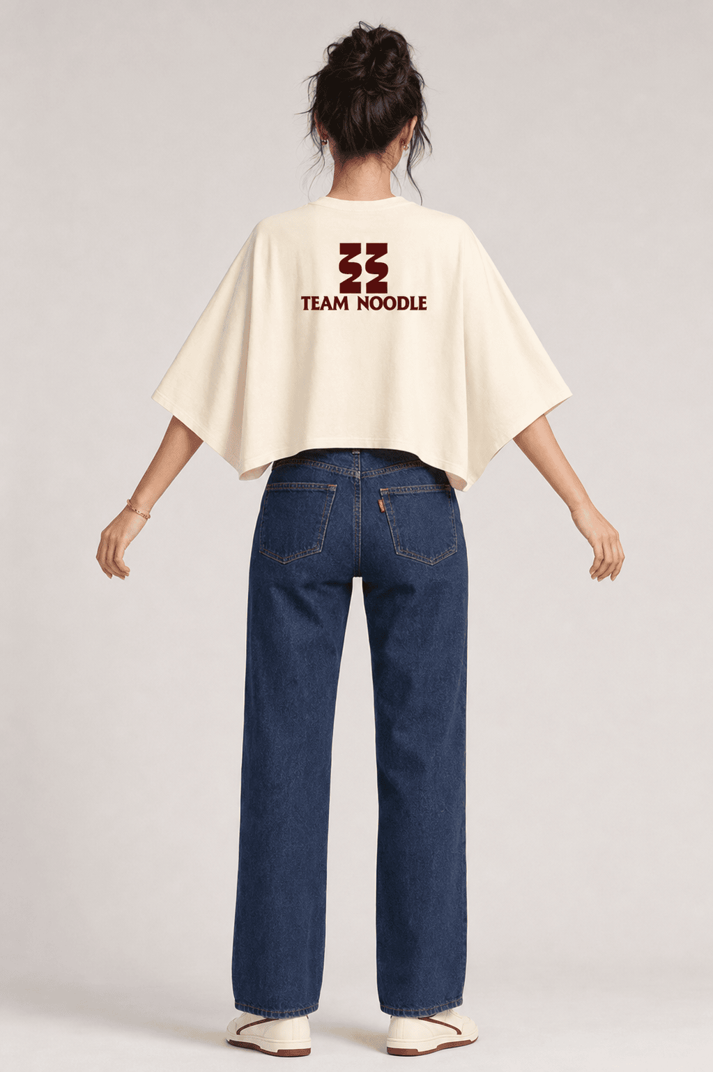 Back view on the model showing the maroon Team Noodle logo across the cream batwing tee