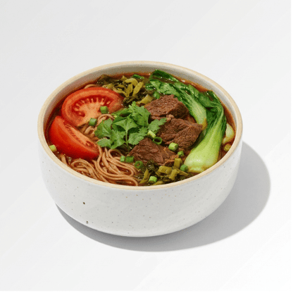 Bowl of Taiwanese tomato beef noodle soup with sliced beef, tomato, bok choy and pickled greens